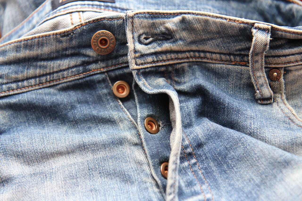 heros-img Detailed close-up of classic blue denim jeans with visible buttons.