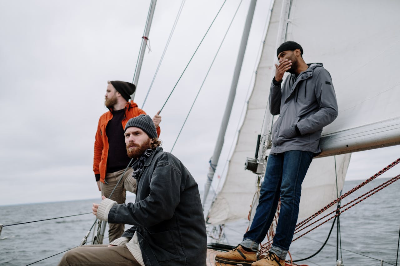 about-us-02 Three men enjoy a thrilling adventure on a sailing boat, captured amidst the ocean's expanse.