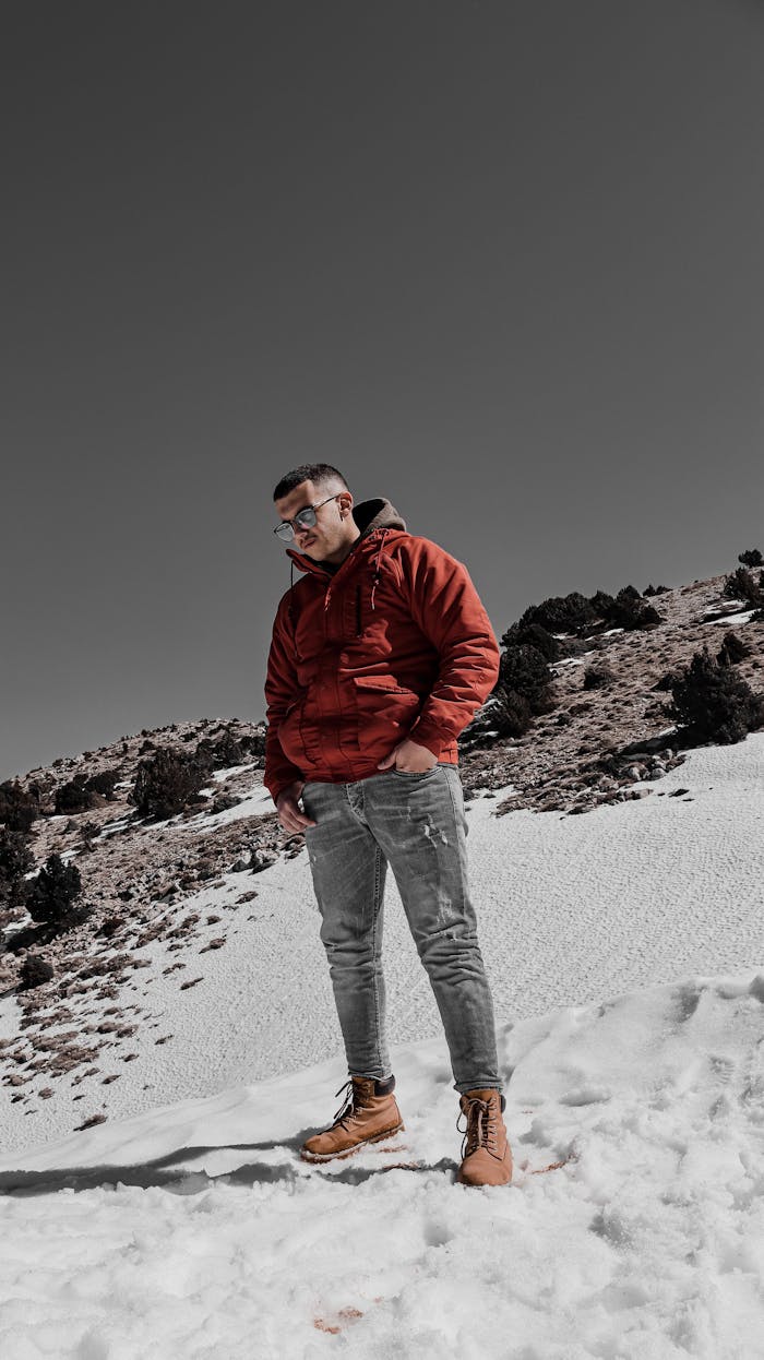 Mastering the First Impression: Your intriguing post title goes here Outdoor winter portrait of a man standing on a snowy hill in a red jacket, looking thoughtful.